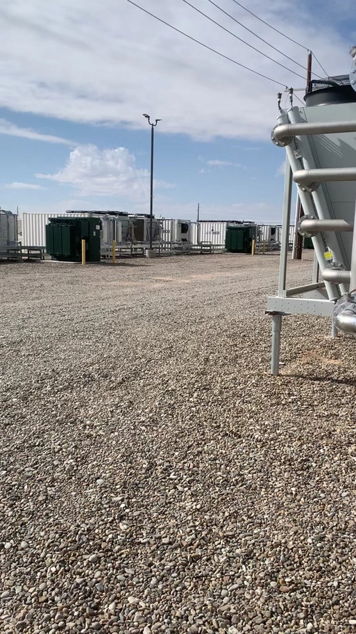 Aerial view of a large-scale solar panel installation near a mining farm.